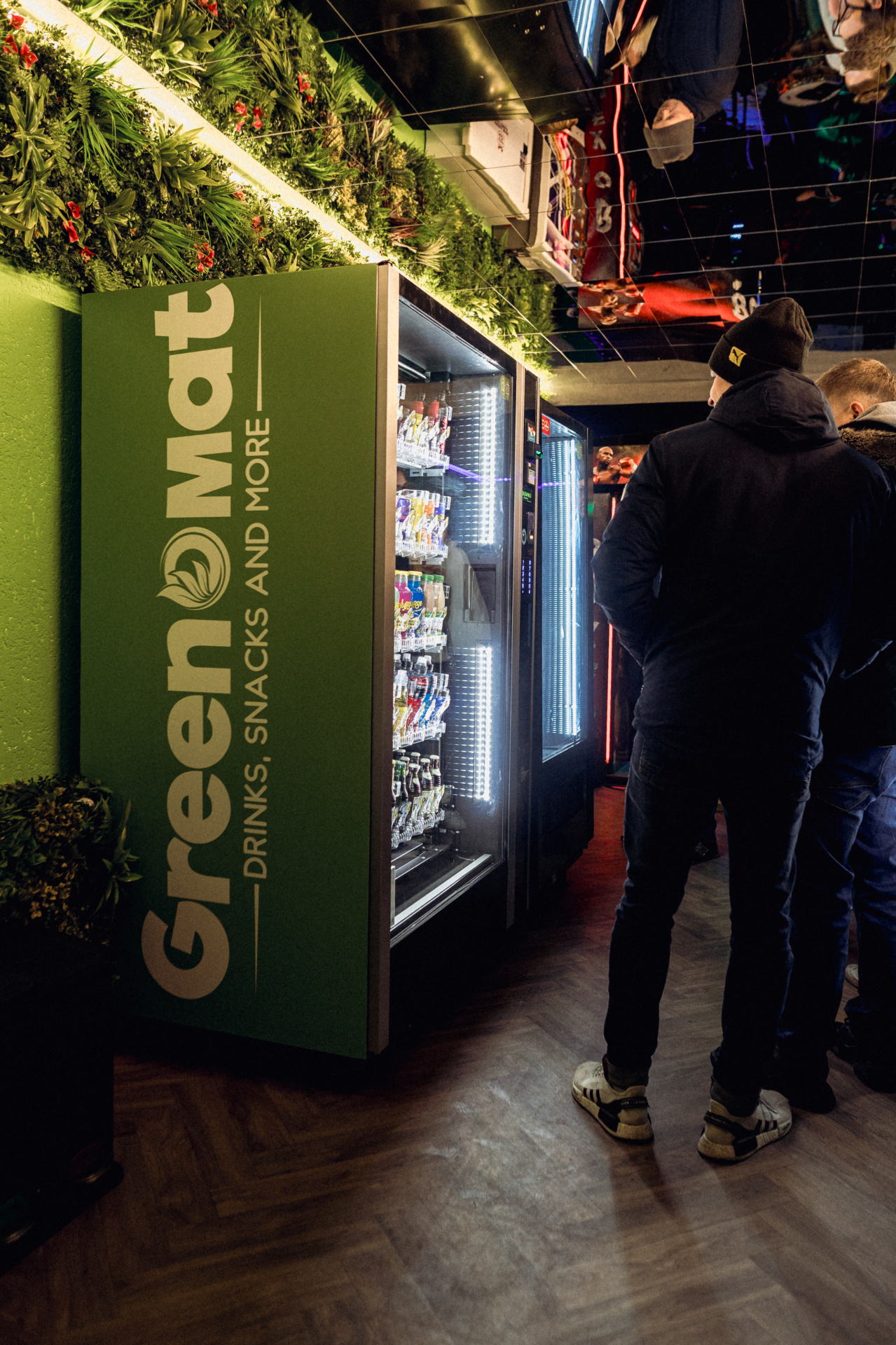 Greenomat Snack- und Getränkeautomat mit Greenomat-Branding und begrünter Wand